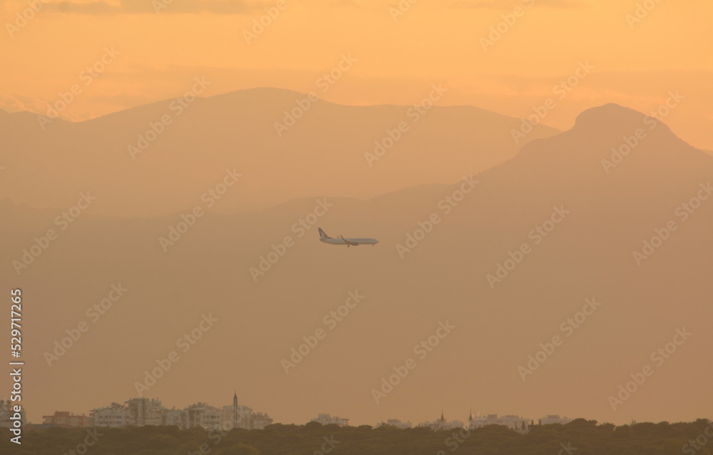 Airplane at sunset against the backdrop of mountains