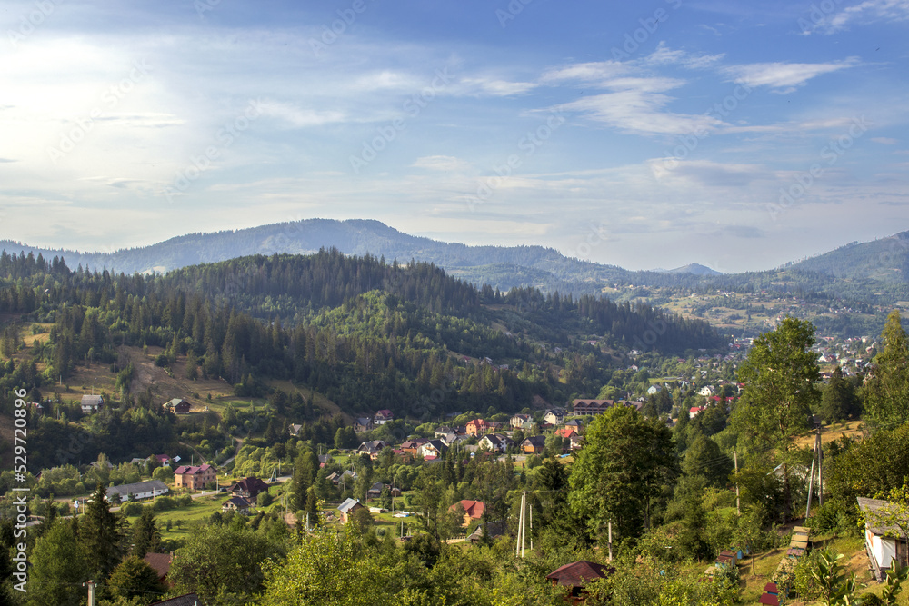 Obraz premium The mountain landscape with settlements in the background in the Carpathians. Sunny valley in the mountains. Beautiful Ukraine. 