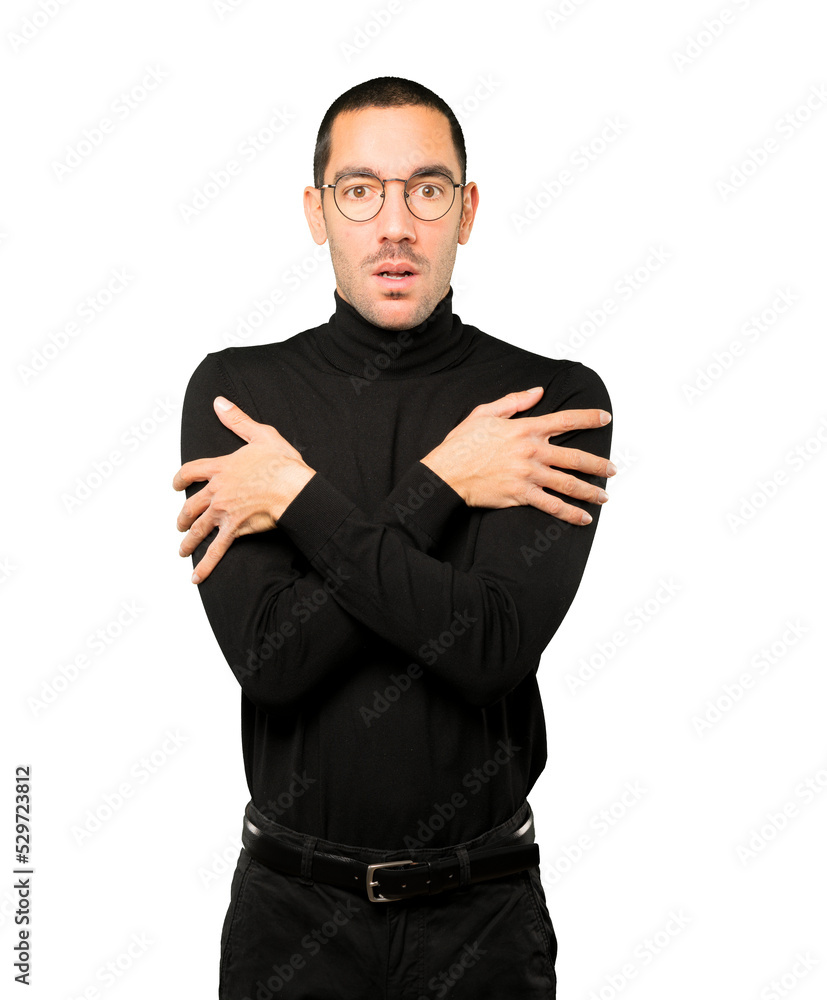 Concerned young man making a gesture of being cold Concerned young man making a gesture of being cold