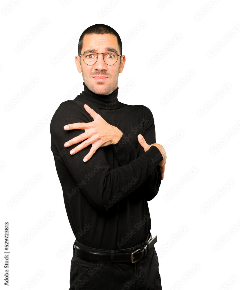 Concerned young man making a gesture of being cold Concerned young man making a gesture of being cold
