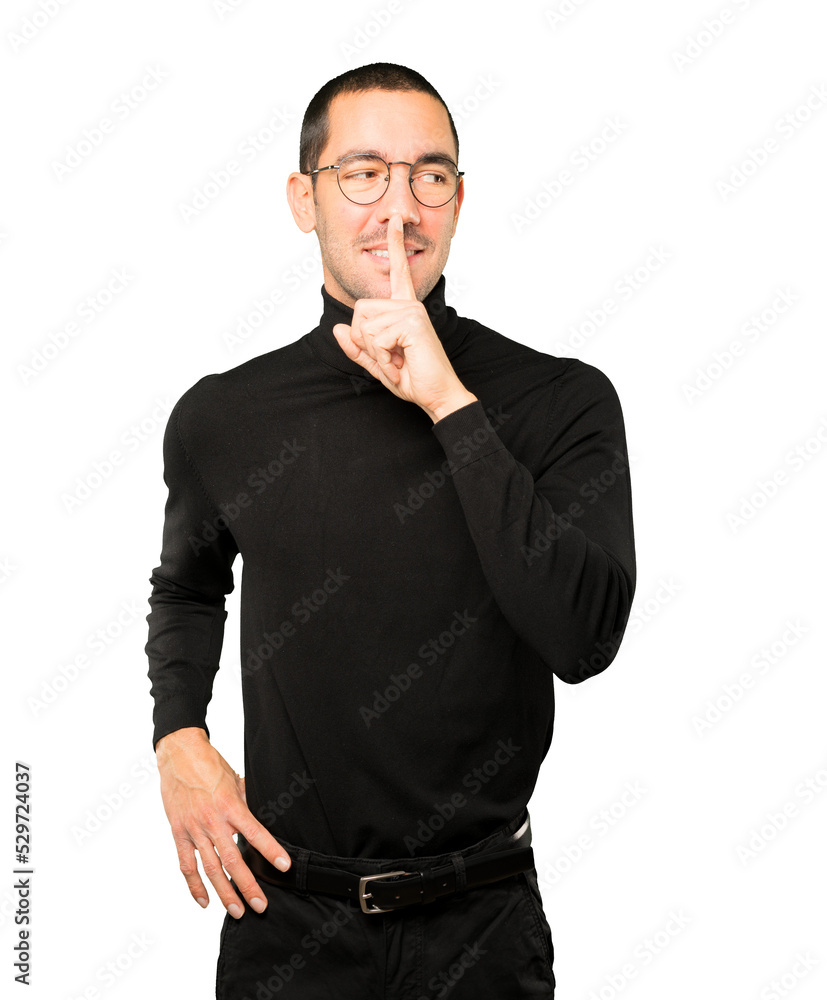 Happy young man asking for silence gesturing with his finger Happy young man asking for silence gesturing with his finger