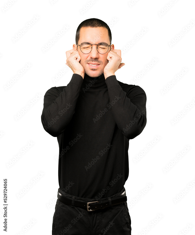 Young man worried about loud noises and covering his ears Young man worried about loud noises and covering his ears