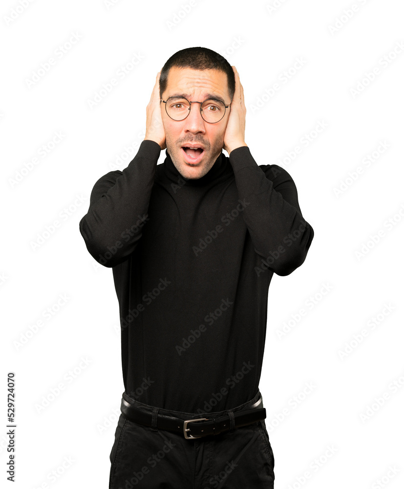 Concerned young man worried about loud noises and covering his ears Concerned young man worried about loud noises and covering his ears