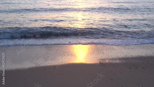 Ondas com reflexo do pôr do sol na areia da praia