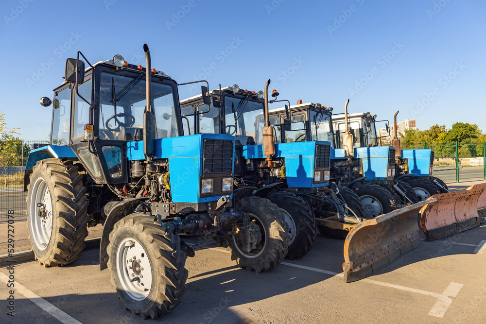 Obraz premium Road service multi-purpose blue wheel tractors in row on the parking lot