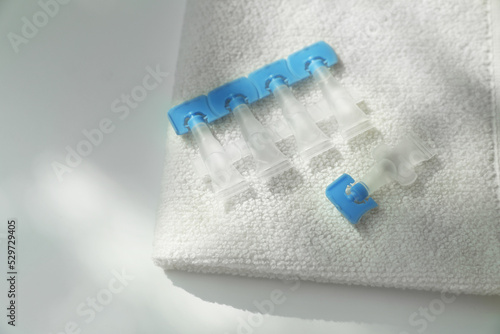 Single dose eye drops and towel on white table, closeup