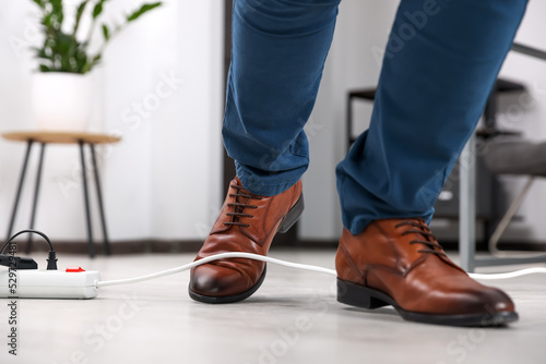 Fotografi Man tripping over cord in office, closeup