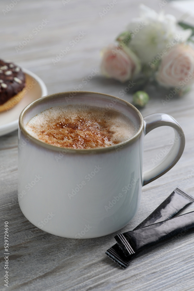 Delicious coffee in cup and sugar packets on white wooden table Delicious coffee in cup and sugar packets on white wooden table