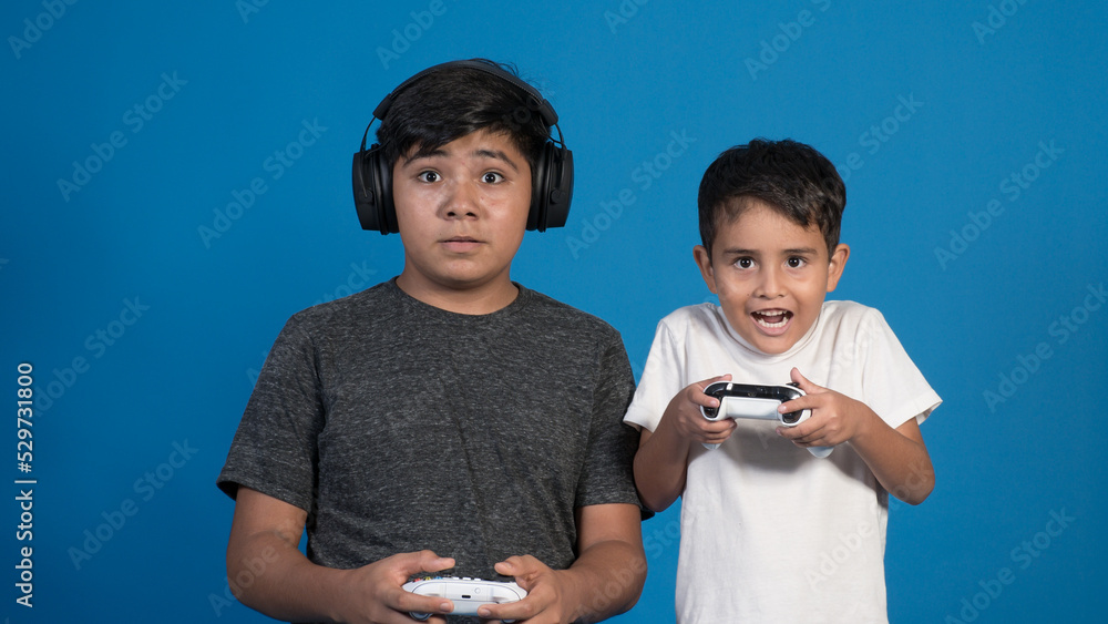 Retrato de estudio de dos niños jugando a videojuegos con auriculares y ...