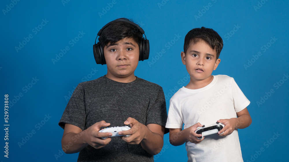 Retrato de estudio de dos niños jugando a videojuegos con auriculares y ...