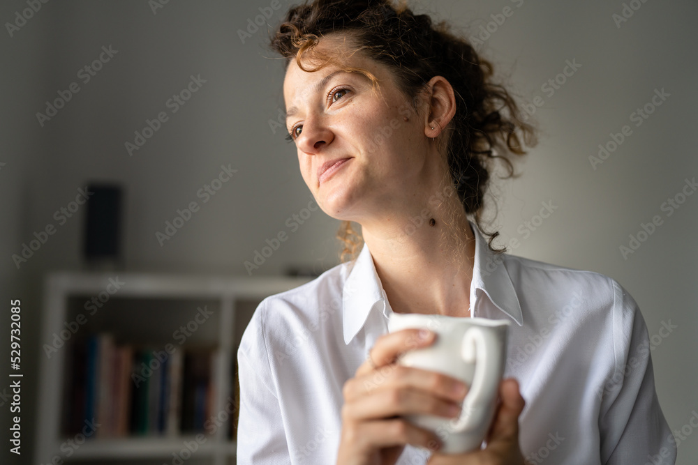 Woman standing in the office with cup of coffee morning daily routine Woman standing in the office with cup of coffee morning daily routine