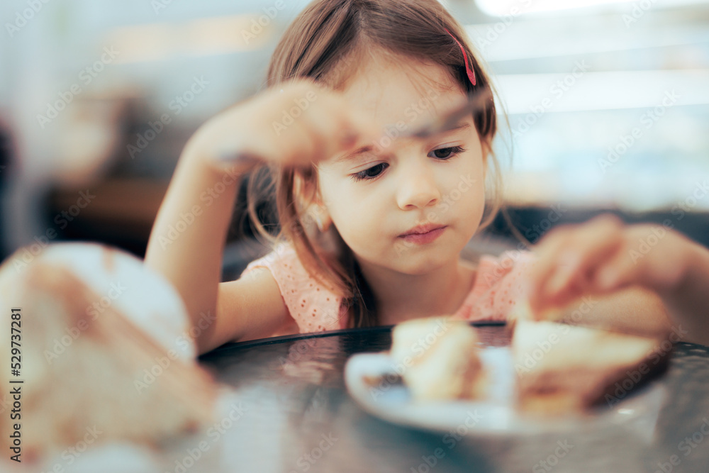 Toddler Girl Focused on Eating on a Restaurant. Little child feeling food after eating in a sweetshop
Toddler Girl Focused on Eating on a Restaurant. Little child feeling food after eating in a sweetshop