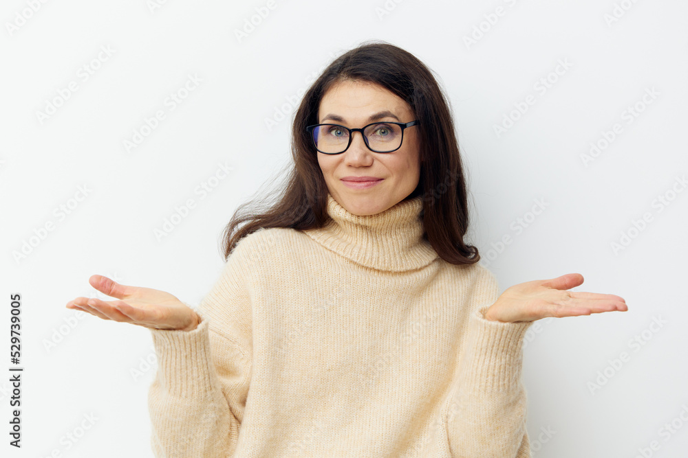 a beautiful, smart, attractive, stylish woman in glasses for vision stands in a warm beige sweater on a light background smiling pleasantly at the camera and spreading her arms to the sides a beautiful, smart, attractive, stylish woman in glasses for vision stands in a warm beige sweater on a light background smiling pleasantly at the camera and spreading her arms to the sides