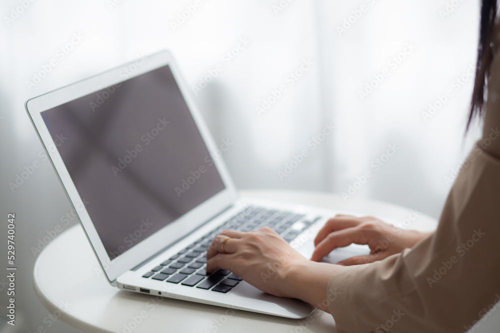 Young asian woman work from home with laptop computer blank screen mockup, freelance is female using notebook with display empty, girl typing keyboard, business and communication concept.