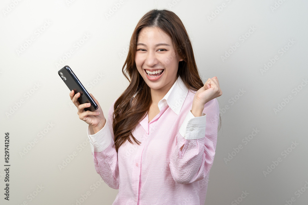Happy Asian woman holding a smartphone and winning the prize. Happy Asian woman holding a smartphone and winning the prize.