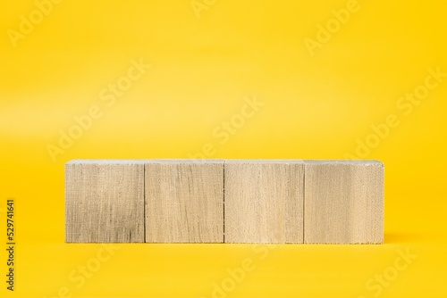 Fototapeta Naklejka Na Ścianę i Meble -  4つの木製のブロックと黄色背景　合成素材

