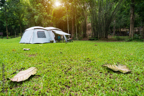 camping cabin tent on grass campground and tree in nature green forest and autumn camp to holiday relax or vacation travel trip with family trekking on lawn and morning sunlight at pha tad waterfall photo