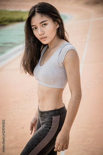 Young strong fit woman showing bicepses portrait in gym, looking away