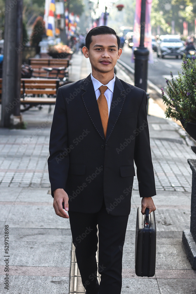 Businessman in formal wear with suitcase walking on the city.