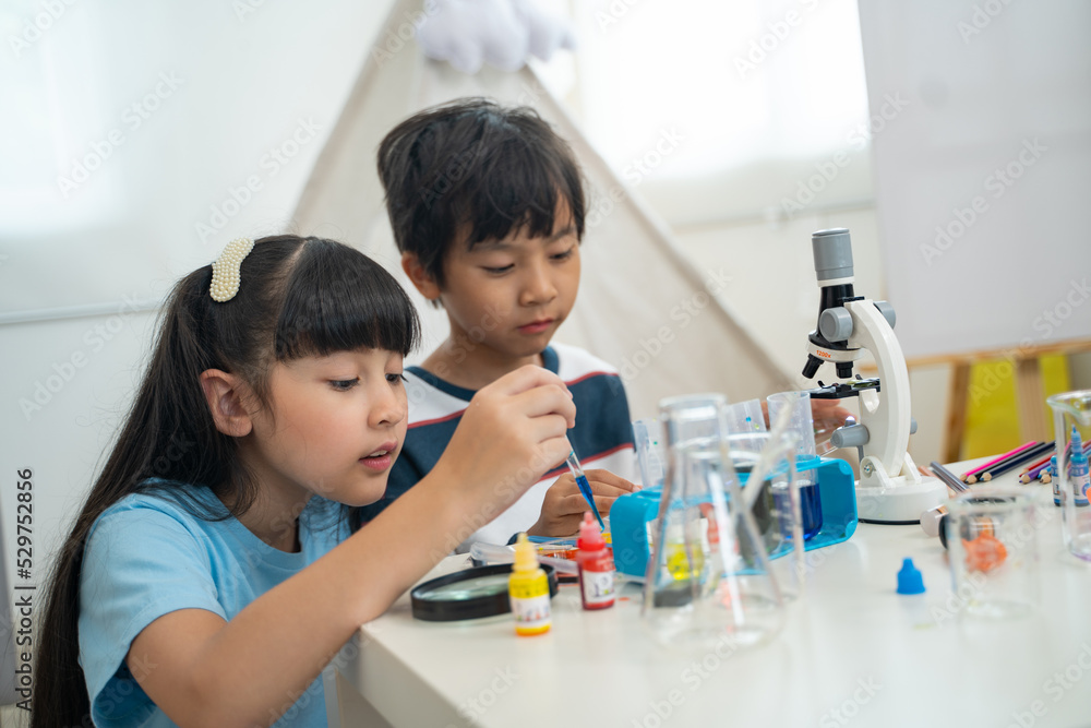 Two little scientists making chemical test with toy microscope in living room Two little scientists making chemical test with toy microscope in living room