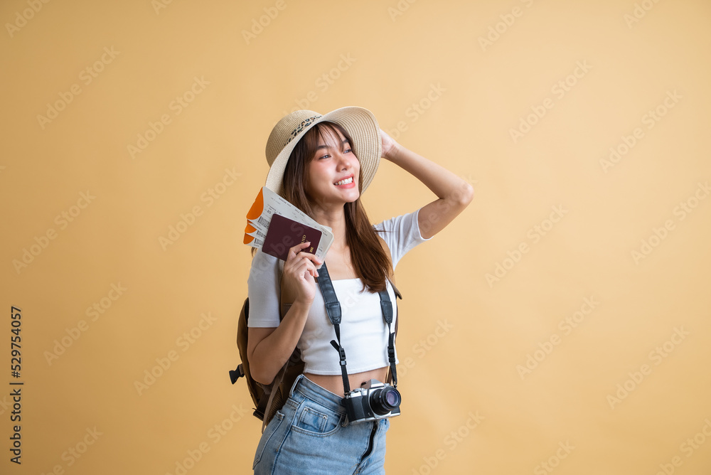 young attractive Asian woman traveler in casual clothes wearing straw hat with backpack, passport, camera and boarding pass ticket, Tourist girl having cheerful holiday trip concept young attractive Asian woman traveler in casual clothes wearing straw hat with backpack, passport, camera and boarding pass ticket, Tourist girl having cheerful holiday trip concept