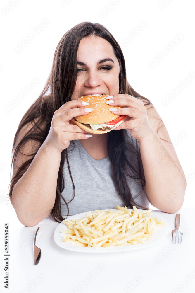 Overweight woman with appetite greedily eats hamburger. Obesity and fast food. Isolated on white background. Vertical. Overweight woman with appetite greedily eats hamburger. Obesity and fast food. Isolated on white background. Vertical.