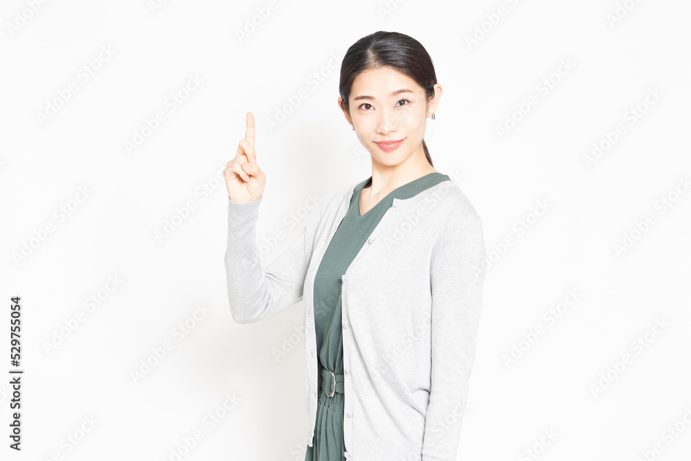 白背景の前に立って、ポイントを示す女性 白背景の前に立って、ポイントを示す女性