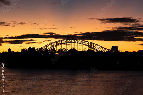 Silhouette of Sydney Harbour Bridge with sunrise glow.