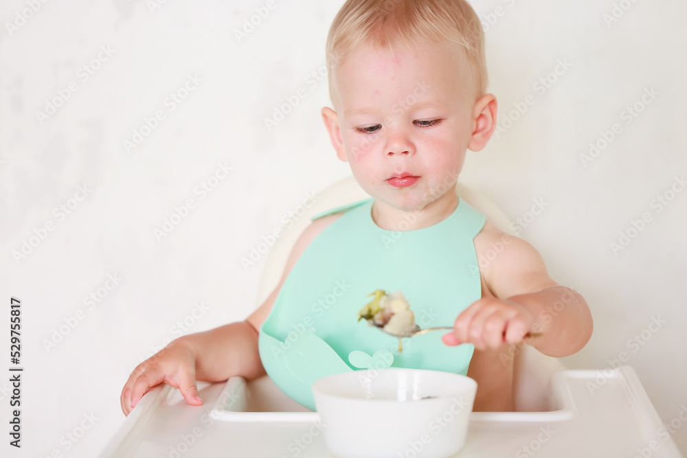 kid eats with a spoon and learns by himself