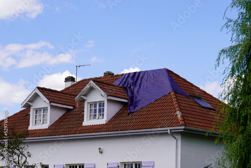 roof needs repairs covered with a tarp waiting for the roofing company to fix after spring summer thunderstorm