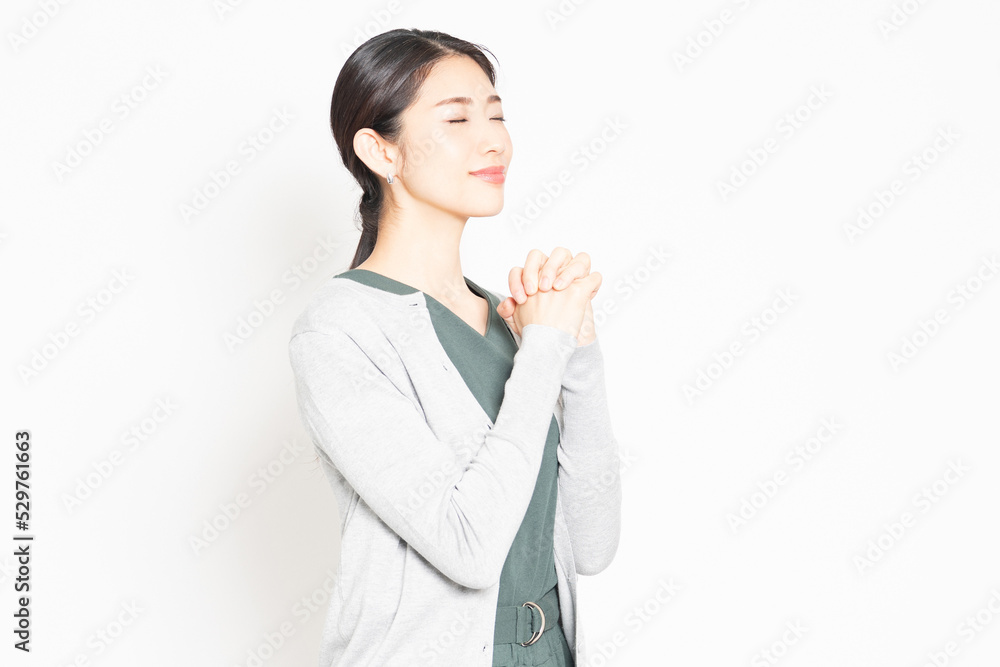 白背景の前で、お願いのポーズをする女性 白背景の前で、お願いのポーズをする女性