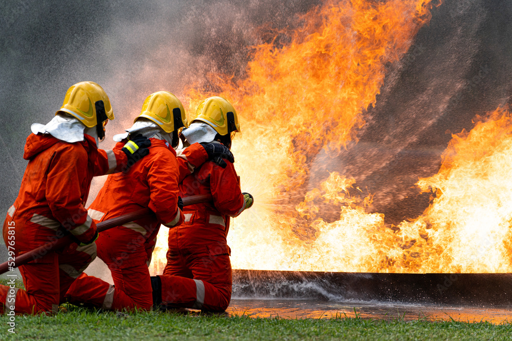 Firefighters or Firemen use extinguisher and spray high pressure water from hose to control fire.Firefighter team training to control fire not to spreading out in gas and oil fire accident simulation. Firefighters or Firemen use extinguisher and spray high pressure water from hose to control fire.Firefighter team training to control fire not to spreading out in gas and oil fire accident simulation.