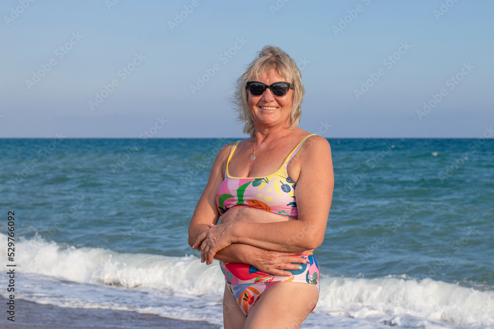 Attractive elegant and happy senior woman standing on the sea beach. Attractive elegant and happy senior woman standing on the sea beach.
