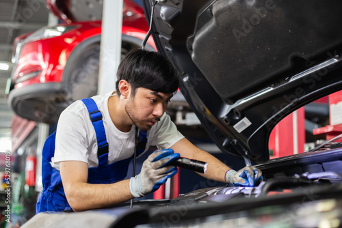 Transportation repair service concept, Repairman auto mechanic using flashlight to check for damage inside engine. man worker service engine mechanic garage.