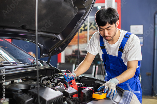 Transportation repair service concept, Repairman auto mechanic Checking battery power of car after has been used inside engine. man worker service engine mechanic garage.