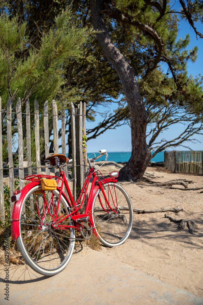 Vieux vélo rouge en bord de mer sur le littoral en France.