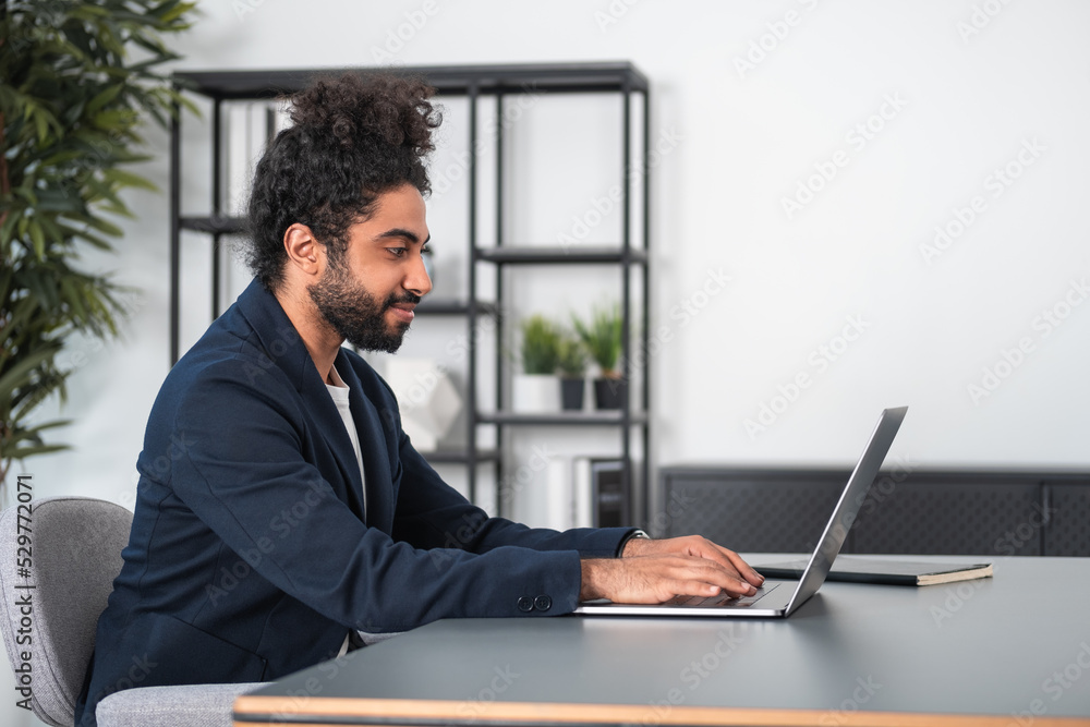 Arab businessman typing on laptop, home office interior Arab businessman typing on laptop, home office interior