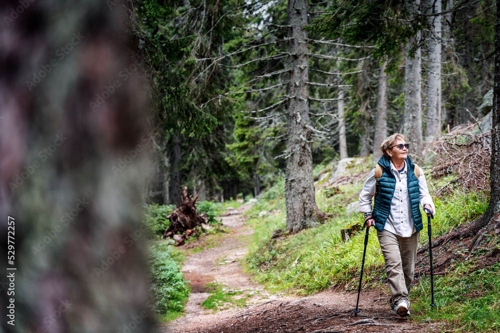 Active happy mature senior woman walking in beautiful autumn forest