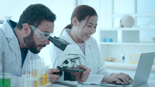 Biotechnology researcher scientist working look microscope in the medical development laboratory for vaccine development. Scientist of laboratory researcher holding medical glass bottle