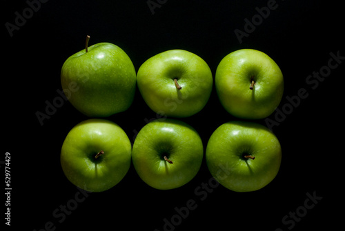 Six green apples isolated on a black background, top view.