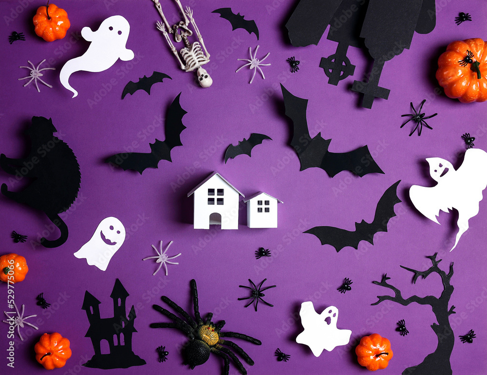 Small toy house surrounded by Halloween decorations on purple background.