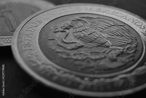 Coin of 5 Mexican pesos close up. Peso of Mexico. Reverse of coin with coat of arms of country. Eagle and snake. Dark black and white background. News about economy or currency. Loan and money. Macro