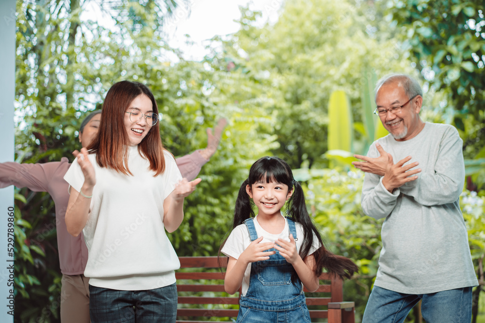 Fototapeta premium Asian happy family stay home outside .backyard. Little girl with grandparents and mother dancing having fun together practice. laughing, enjoy parenting activity relationship in house.