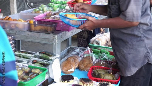 Indonesian street vendors who sell various kinds of sweet and salty cakes also sell wrapped rice.  photo