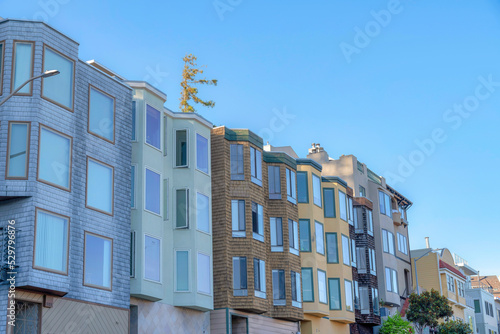 Small apartment buildings with different wall sidings and window structures in San Francisco, CA