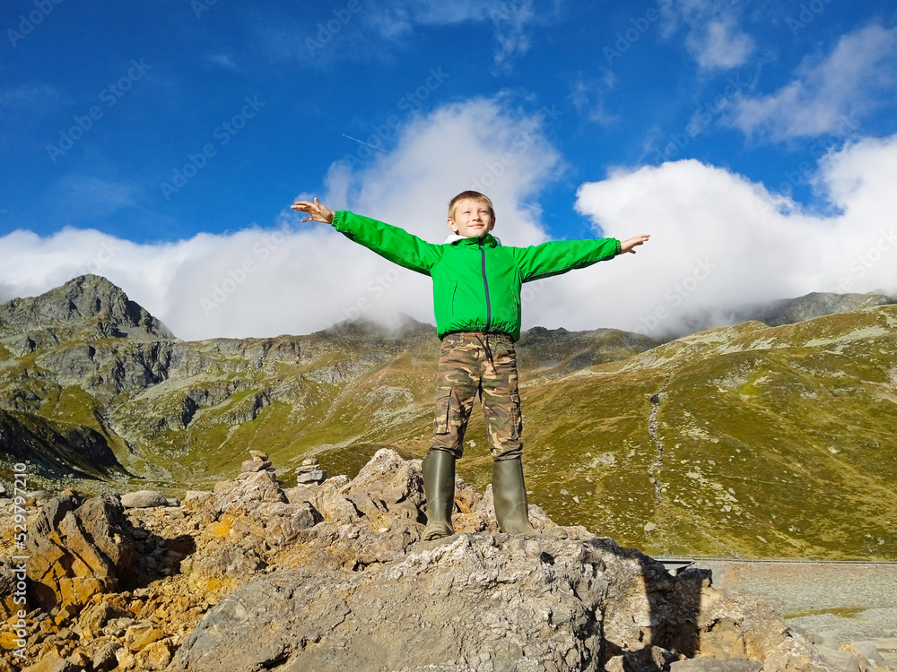 Teenager boy standing on top of a mountain with raised hands