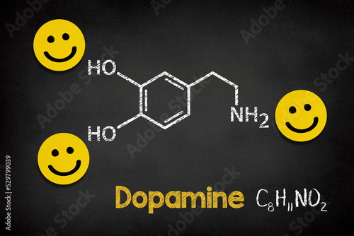 Chemical formula of dopamine with smile icons on blackboard photo