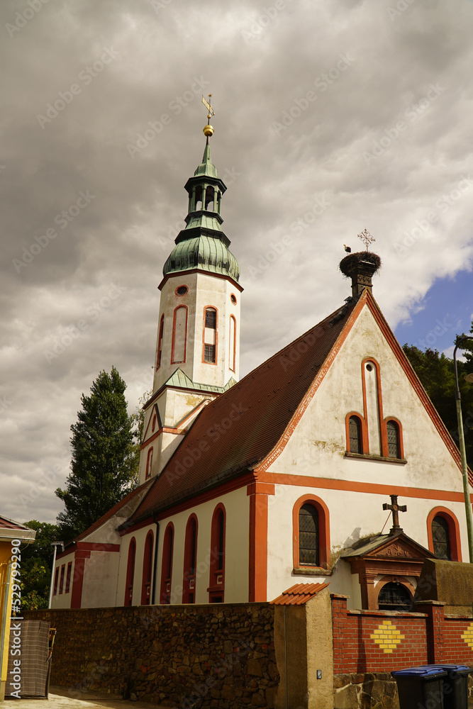 Naklejka premium Protestant parish church with a large stork nest on the roof in Otterwisch near Leipzig, Germany. The church dates back to the 12th century and has been rebuilt several times. 