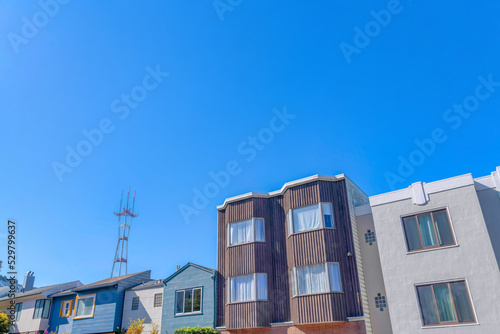 Adjacent suburban houses against the Sutro Tower and clear blue sky background at San Francisco, CA