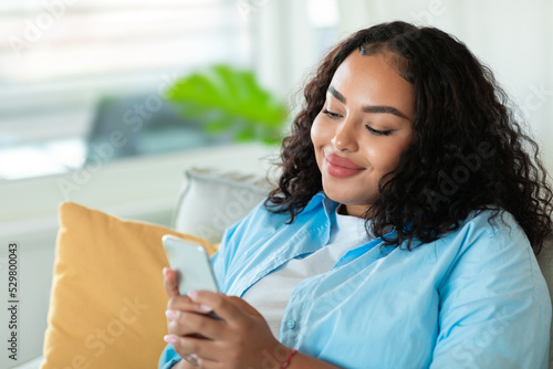 Black Woman Using Phone Communicating Texting Sitting On Couch Indoors